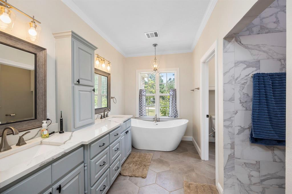 This primary bathroom is the perfect place to relax and unwind after a long day. Custom built cabinets, double sinks, and a large free standing soaking tub are sure to provide you with the ultimate spa-like experience. Plus, the large window next to the tub lets in plenty of natural light for an extra tranquil atmosphere. When it\'s time for a refreshing shower, you\'ll love having access to a spacious walk-in shower.