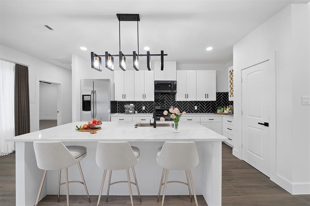 This stunning custom kitchen will feature gorgeous quarts countertops, soft-closing cabinetry, and sleek black herringbone backsplash.