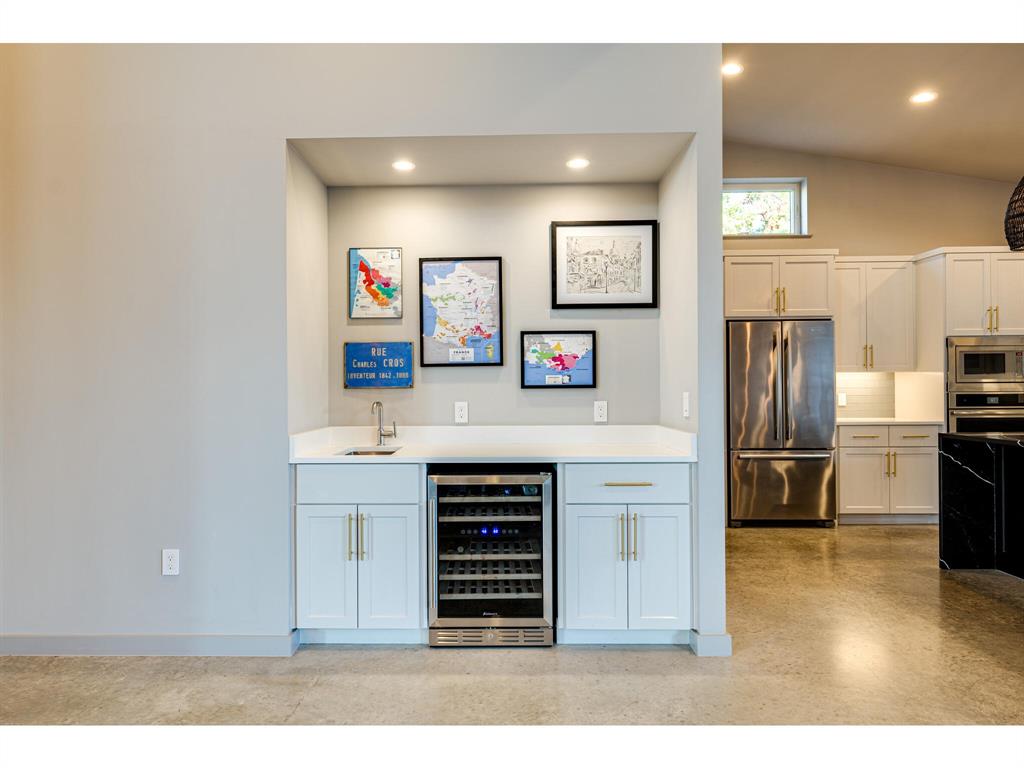 Wet bar with wine refrigerator extends a welcome into this incredible home