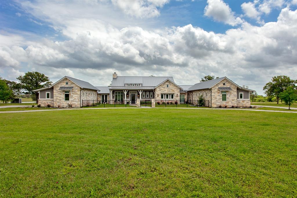 Heaven is not that far away with this gorgeous custom home and 175 acres of land! No details were left out of this custom built home with an open concept living area and an oversized Chef kitchen complete with 2 islands, farmhouse sink, gas stove, double ovens, pendulum lights and a HUGE pantry! Two dining areas, two living areas and separate office. The family room has vaulted ceilings w/white shiplap, book shelves, recessed lighting, an oversized Austin Stone fireplace and wall of windows. The primary bedroom closet offers an abundance of space, built in dressers and a lighted vanity. The Austin Stone is showcased throughout the home in the study and primary bedroom for added detail and warmth. Two garages w/six bays, relax on your back patio overlooking the sparkling pool and lake with an outdoor kitchen, fire pit and space to host gatherings. This property comes with a barn and greenhouse. Pipe fencing at the entry way, perimeter fencing and house is surrounded by fencing.