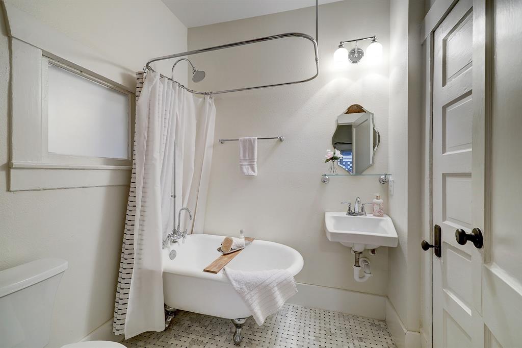Original bathroom is now jack and jill,  used as powder and bath for original primary bedroom, with clawfoot tub, marble tile floor, and shiplap accent wall.