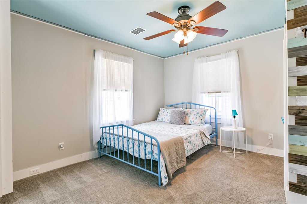 The upstairs bedroom boasts a ceiling fan and a beautifully crafted light fixture. It is enhanced with triple windows adorned with both blinds and curtains, allowing for abundant natural light and privacy when desired.