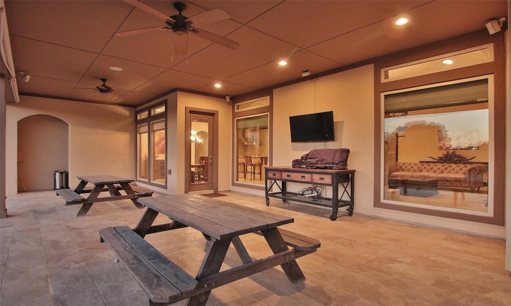A sunset view of the covered patio and a view of the large windows in the back of this house!