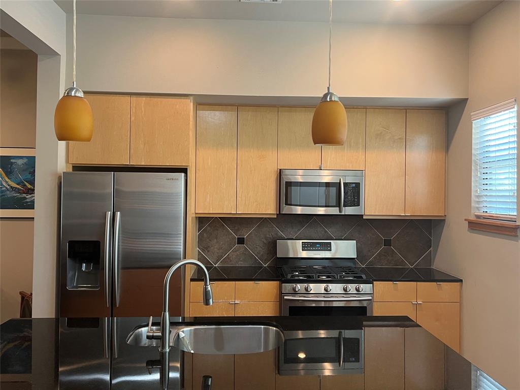 Kitchen view with hanging light sconces, Granite counters and Samsung stainless appliances.