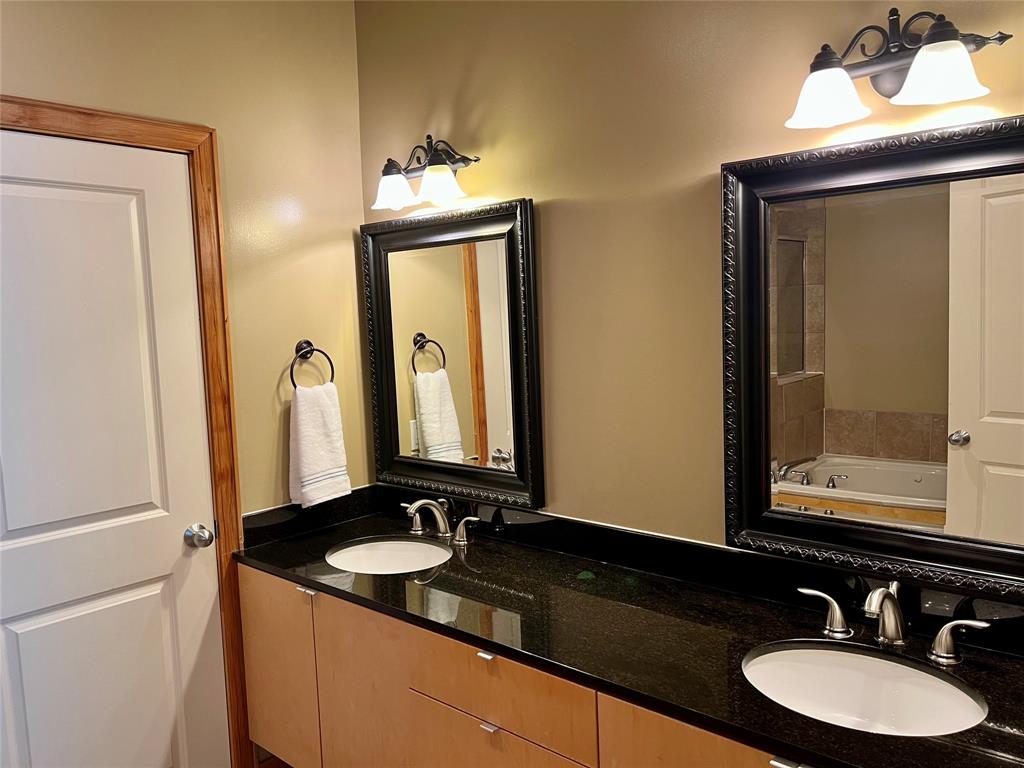 Primary bathroom features dual sinks, Granite counters, brushed nickel hardware and tile flooring.
