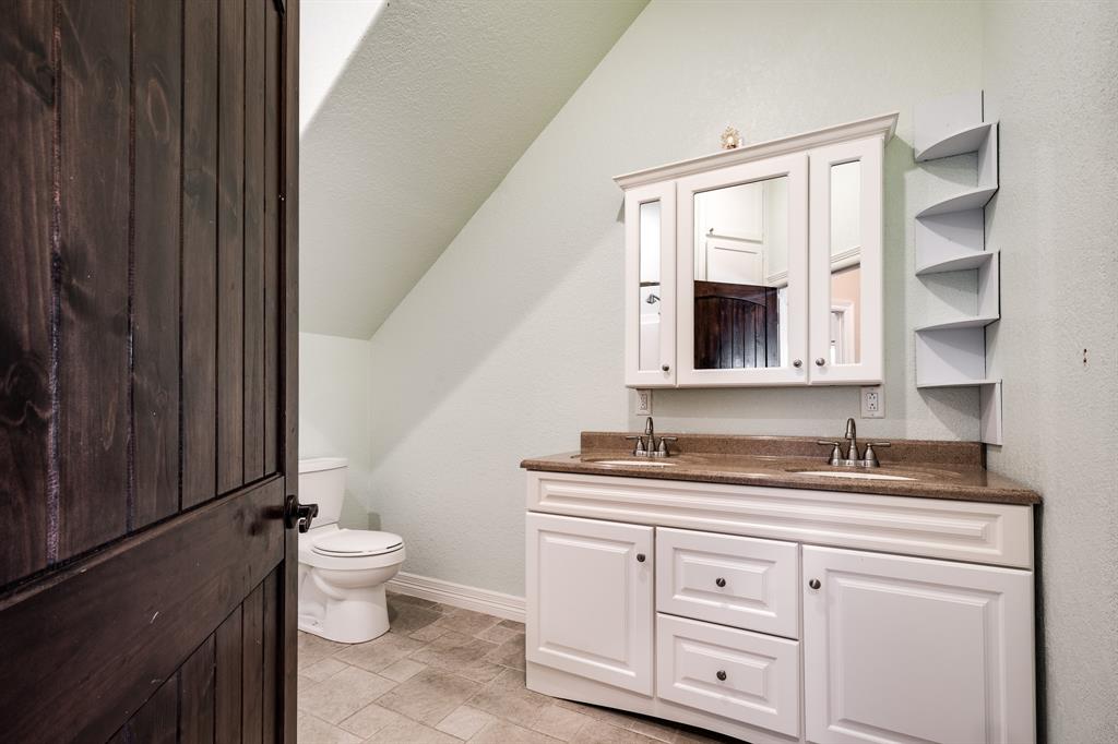 36\' doorway leading into the large bathroom with double-sink vanity, triple-mirrored cabinet over sinks, and corner shelf for extra storage.