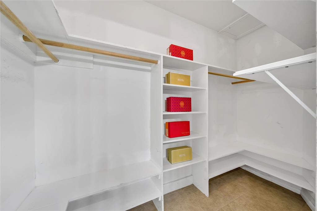 Large primary closet with plenty of hanging space and built-in shelves for storage and organization.