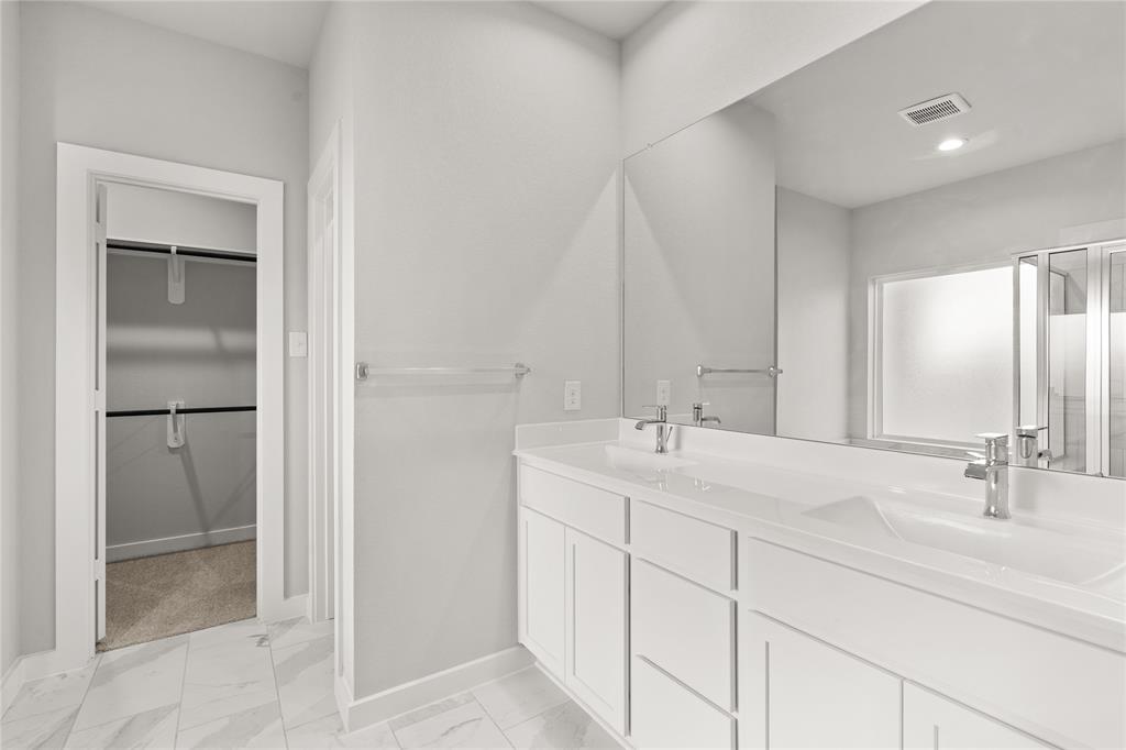 This primary bathroom is definitely move-in ready! Featuring white stained cabinets with light countertops, spacious walk-in closet with shelving, high ceilings, custom paint, sleek and dark modern finishes.