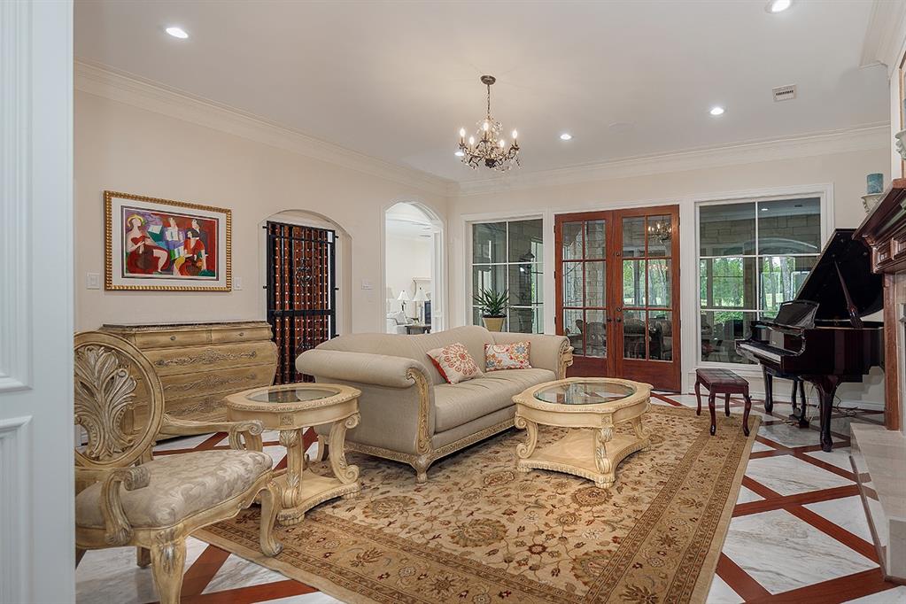 The formal living has a gated wine grotto, fireplace and doors that lead to a screened-in sunroom