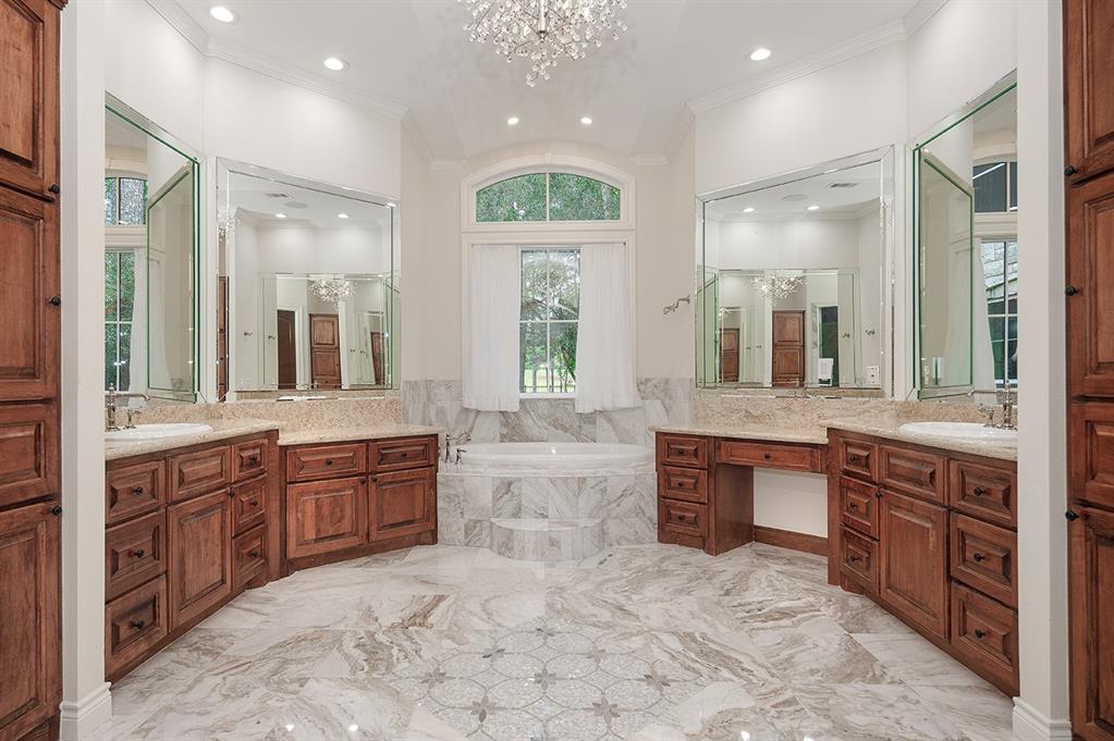 Luxurious bath with soaking tub, dual sinks, vanity area and decorative inlay centered on the tile floor