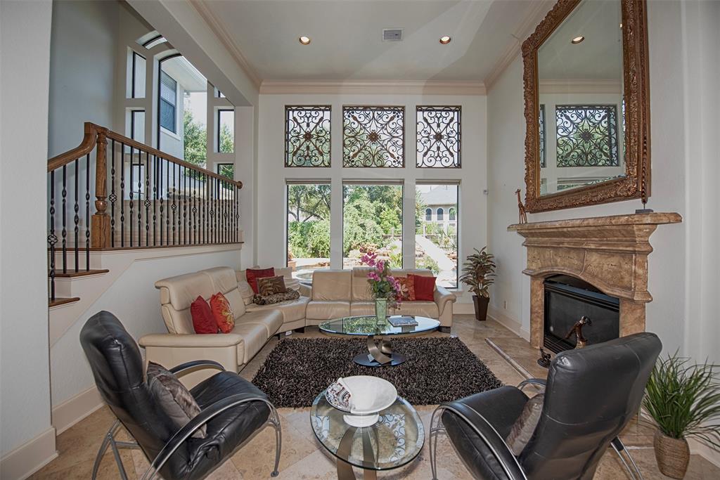 The formal living room is bathed in natural light and features an elegant fireplace, 20-ft soaring ceiling and beautiful views of the pool and landscaped backyard.