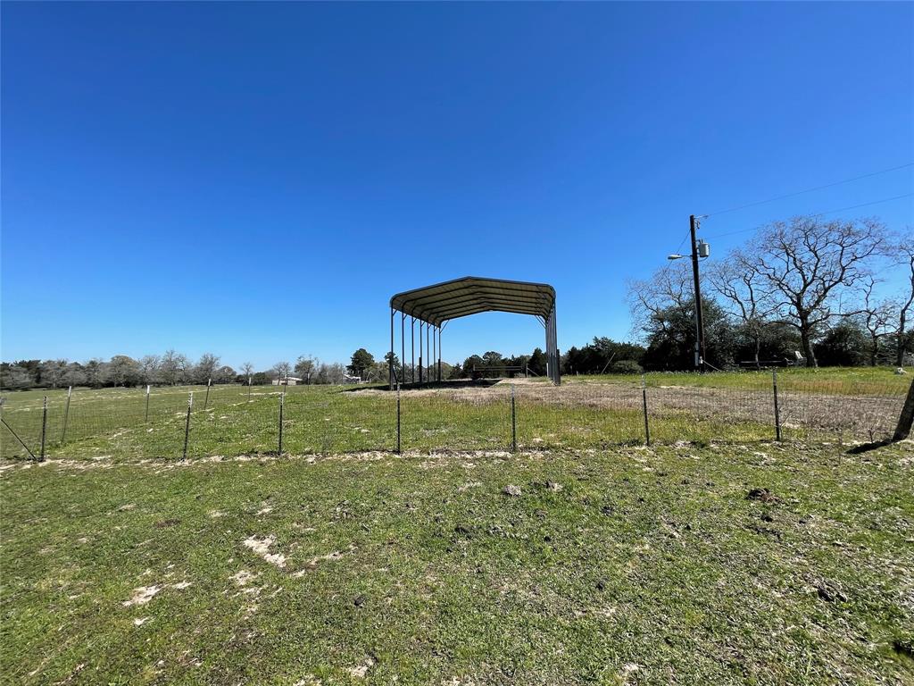 The giant metal carport is high enough for an RV or travel trailer providing the perfect coverage.  The soil is super sandy with a clump of trees close by for shade.  The water well is adjacent to the carport.