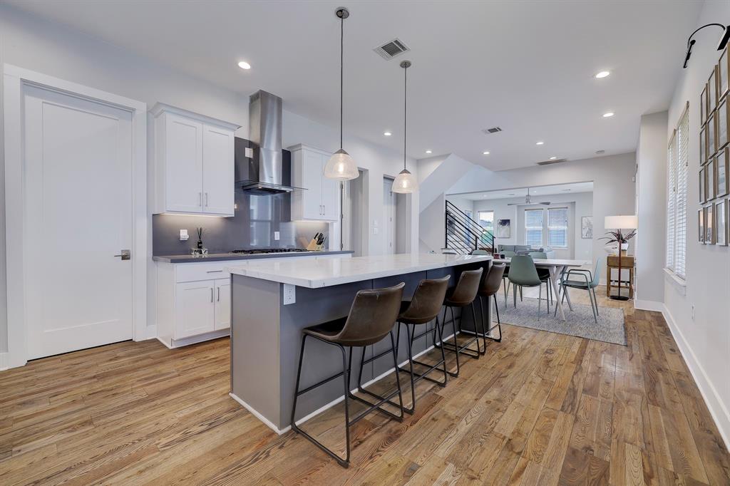 The spacious kitchen island, featuring a stunning waterfall edge design, not only provides ample counter space for meal preparation but also adds a touch of modern sophistication to the entire kitchen space.