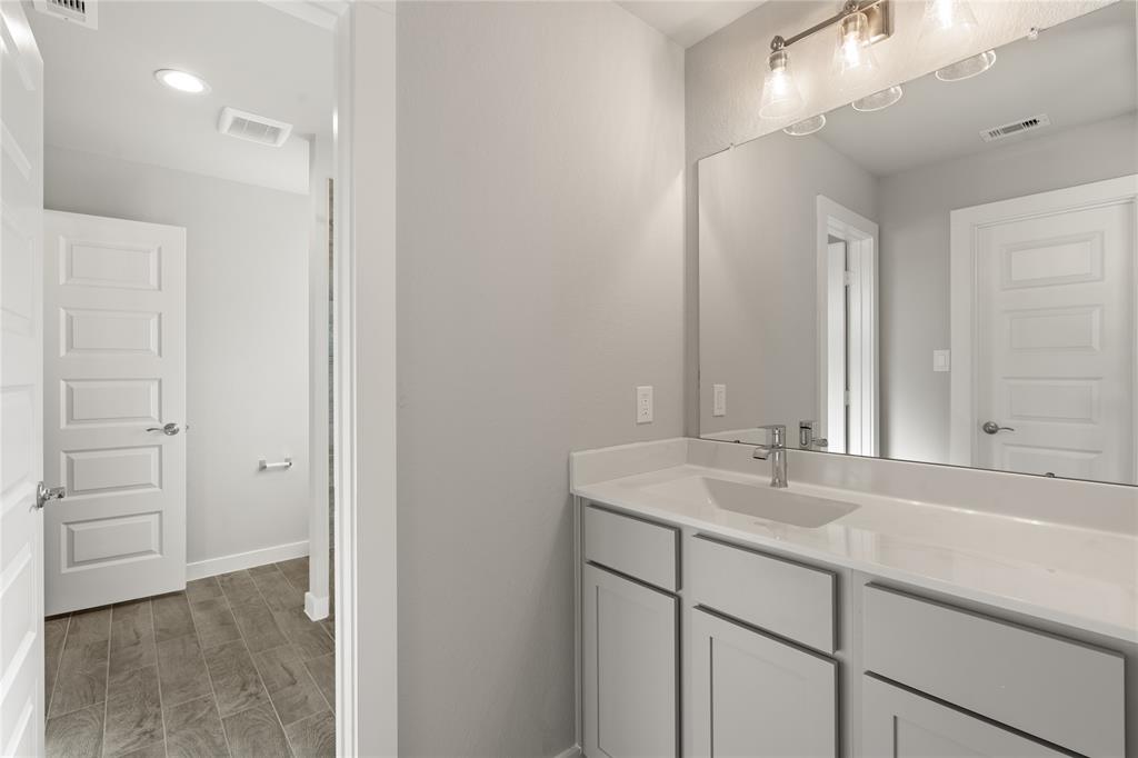 Secondary bath features tile flooring, bath/shower combo with tile surround, light wood cabinets, beautiful light countertops, mirror, sleek fixtures and modern finishes!