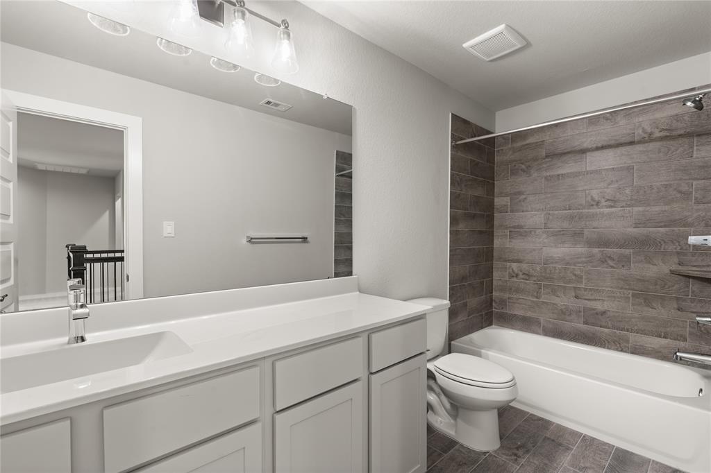 Secondary bath features tile flooring, bath/shower combo with tile surround, light wood cabinets, beautiful light countertops, mirror, sleek fixtures and modern finishes!