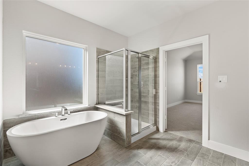 This master bathroom is definitely move-in ready! Featuring framed walk-in shower with tile surround, separate garden tub for soaking after a long day with custom tile detailing, custom paint, sleek modern finishes!