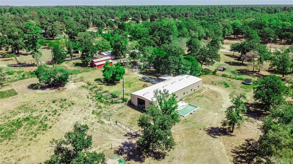 RARE opportunity to own over 23 unrestricted acres in Magnolia, TX.  Three unique buildings, Red Barn, along with a 1,224 sqft cabin, offer endless options to make this property your own.  The 3B/2B home radiates in design and coziness.  Nearby  you'll discover a 120x40 workshop w/rolling doors, the option to close off to create 2 separate spaces,1/2 bath & fenced in area out back. In-ground pool just outside is the perfect spot for cooling off/hosting gatherings!  The Red "party" barn is ready for your art studio/horses.  Two additional buildings that once served as classrooms have mini-split for year round comfort. This space could be a car collectors dream, personal retreat, office space, the options are endless!  Additional office space nearby w/2 bathrooms, garage door and space for dirt bikes, ATV's.  Fenced/cross fenced, 3 p power, 3 septic systems & 3 ponds. Located just 2.4 miles to 1488 and all local amenities. Zoned to Magnolia ISD.  7 buildings total, 2 potential tear downs