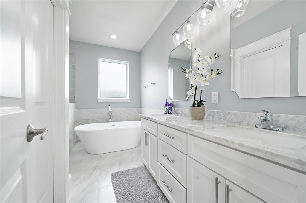 The luxurious primary ensuite bath boasts gorgeous tile floors, a spacious soaking tub, a glass-enclosed shower, a separate closet, and a full vanity area complete with marble countertops, dual sinks, and built-in cabinets.