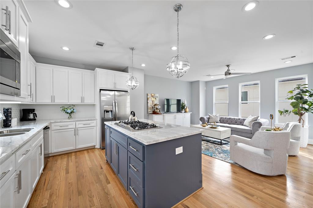 A chef's dream, the gourmet kitchen is thoughtfully designed with marble countertops, a large island with a gas cooktop, modern stainless steel appliances, and a spacious walk-in pantry.