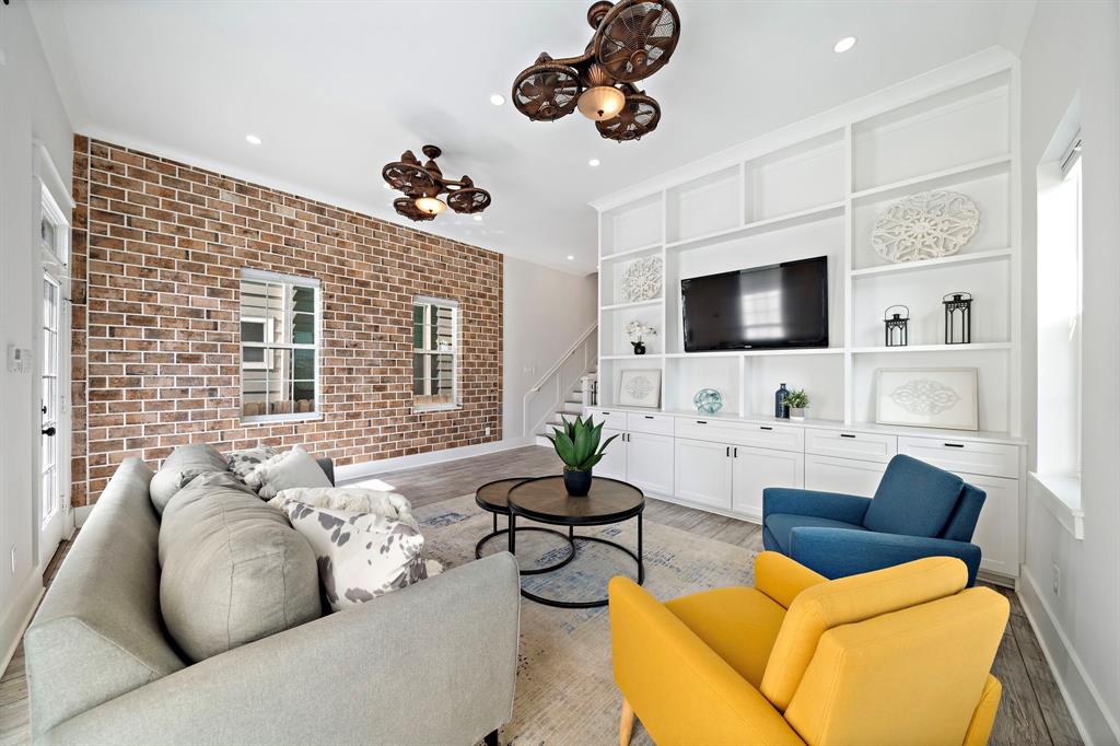 Leave guests in awe as they gather in the living room flaunting a stunning brick accent wall, tall ceilings, and a staircase leading to second-floor bedrooms.