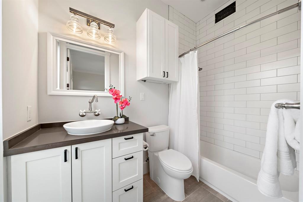 The secondary bedroom features a full ensuite bath with a vanity area with quartz counters, multiple built-ins, and an alcove tub and shower adorned with sleek tile surround.