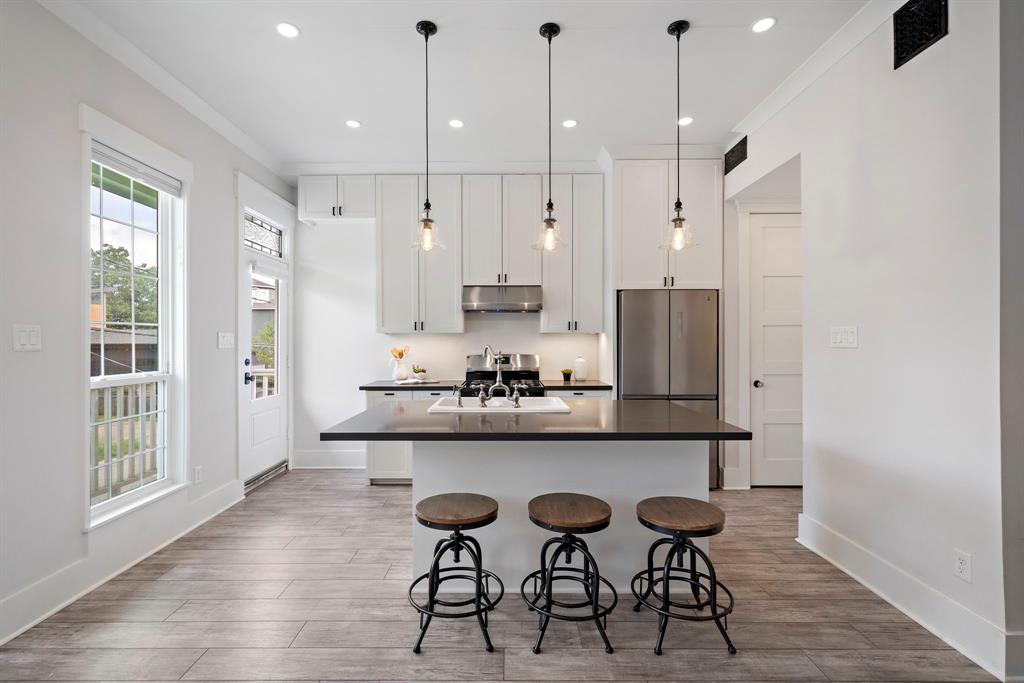 The garage apartment features an open kitchen with quartz countertops, stainless steel appliances, a pantry, laundry, multiple cabinetry, and an expansive center island with a custom sink and ample space for seating.