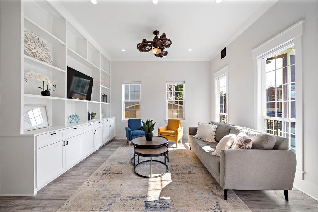 Step into the living area anchored by floor-to-ceiling built-ins, engineered wood floors, and tall windows that flood the space with natural light while providing refreshing outdoor views.