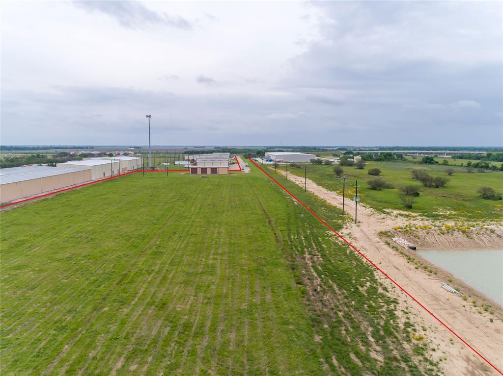 GREAT COMMERCIAL OPPORTUNITY. UNBELIEVABLE +/- 11.501 acres of Land in a commercial/industrial business park. There is a deeded driveway of +/- 60 foot, of which +/- 30 is in full concrete and takes you approximately 1442 foot to the back remaining land of +/- 9.5- acres of land with a +/- 5000 Sqft warehouse. The large metallic structure can be utilized and developed to fit your needs. There is three phase electric service into the structure, but nothing ran once inside.  The structure offers (5) 16' x16' roll up doors, and one 14'x16' roll up door. The front has commercial glass doors and four windows. The space is a blank canvas ready to divide into office space, warehouses, workshops, or what ever your business may need. Then, just decide how to use your remaining acreage or wait and hold for future growth needs. With super easy access to Spur 10, Hwy 90 and US 59. This property is out of the city limits, no city services, speak with Fort Bend county for potential development uses.