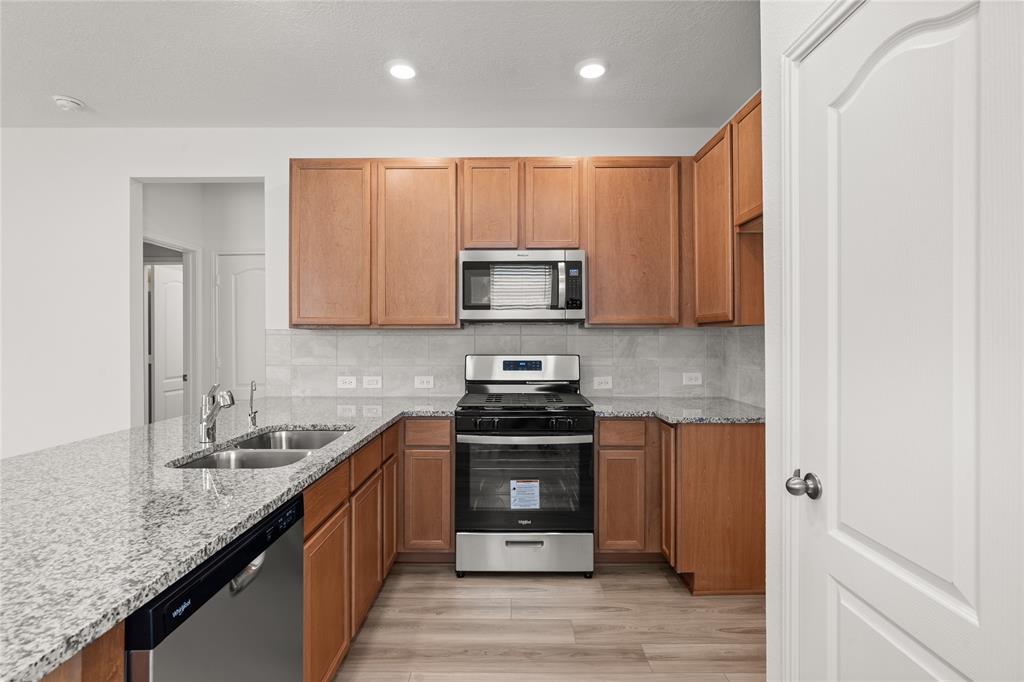 This stunning kitchen displays such a beautiful contrast with the wood stained cabinets, custom neutral paint, granite countertops, light modern backsplash, and SS appliances, kitchen island with extra storage, breakfast bar, recessed lighting, high ceilings and pantry.