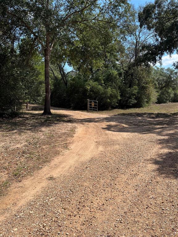 Looking for a quiet, easy maintenance  weekend or full time residence surrounded by 22.610 acres of lovely live oak studded woods accented by walking or riding trails.  Enjoy viewing the native deer and other wildlife along these trails that all come back to the barndominium compound containing 2 ponds, fenced garden or orchard area and circle drive lawn.  The building is divided into a 3/2  2600sq ft. (approx CCAD) home opening to a 20 x 50 ft. porch overlooking the ponds.  The other end of the home opens to a workshop/barn area 2000sq ft. (approx owner) and a covered parking area.  All equipment and tools needed to maintain the property are included and the property already has a wildlife managed plan in place.   Located in the lovely Mossy Oaks Area / Ziemmerscheidt Road and easily accessed from Houston via I-10.  Come see this peaceful property.