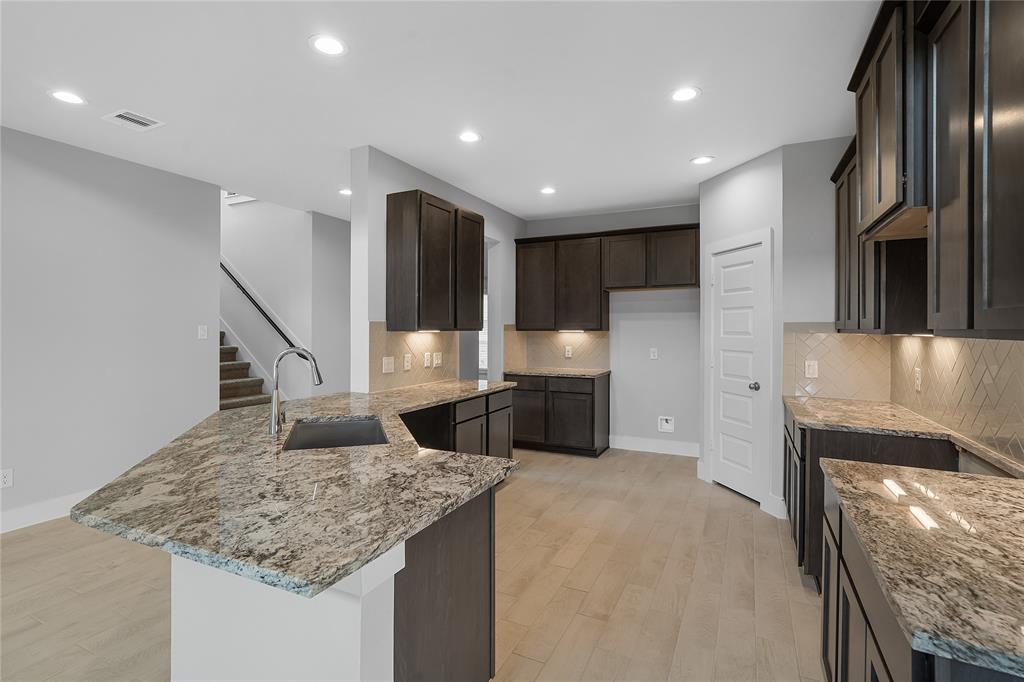 This stunning kitchen displays such a beautiful contrast with the dark stained cabinets, custom neutral paint, granite countertops, light modern backsplash, oversized kitchen island with extra storage, breakfast bar, recessed lighting, high ceilings and walk in pantry.