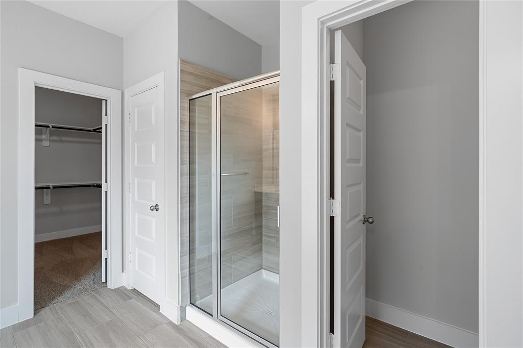 This primary bathroom is definitely move-in ready! Featuring an oversized walk-in shower with tile surround, separate garden tub for soaking after a long day with custom tile detailing, dark stained cabinets with light countertops, spacious walk-in closet with shelving, high ceilings, neutral paint, sleek and modern finishes.