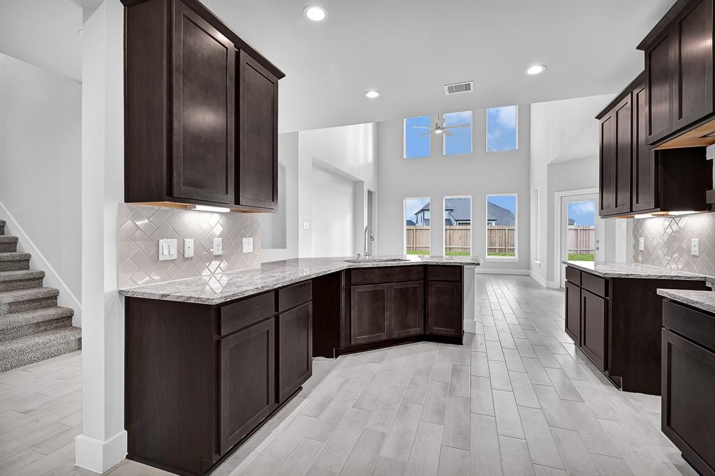 This living room is more like a GREAT room featuring neutral paint, high ceiling, recessed lighting, ceiling fan and an amazing wall of windows providing a lovely view of your backyard to keep an eye out on the kids or pets playing.