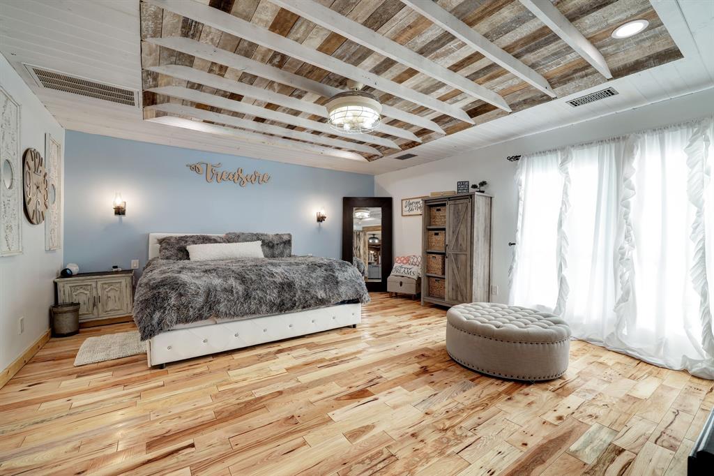 The same beautiful wood flooring flows into the Primary Bedroom en suite. Notice the king size bedroom set. The French doors have views into the front yard. It would be amazing to step out out front for your morning cup of coffee.