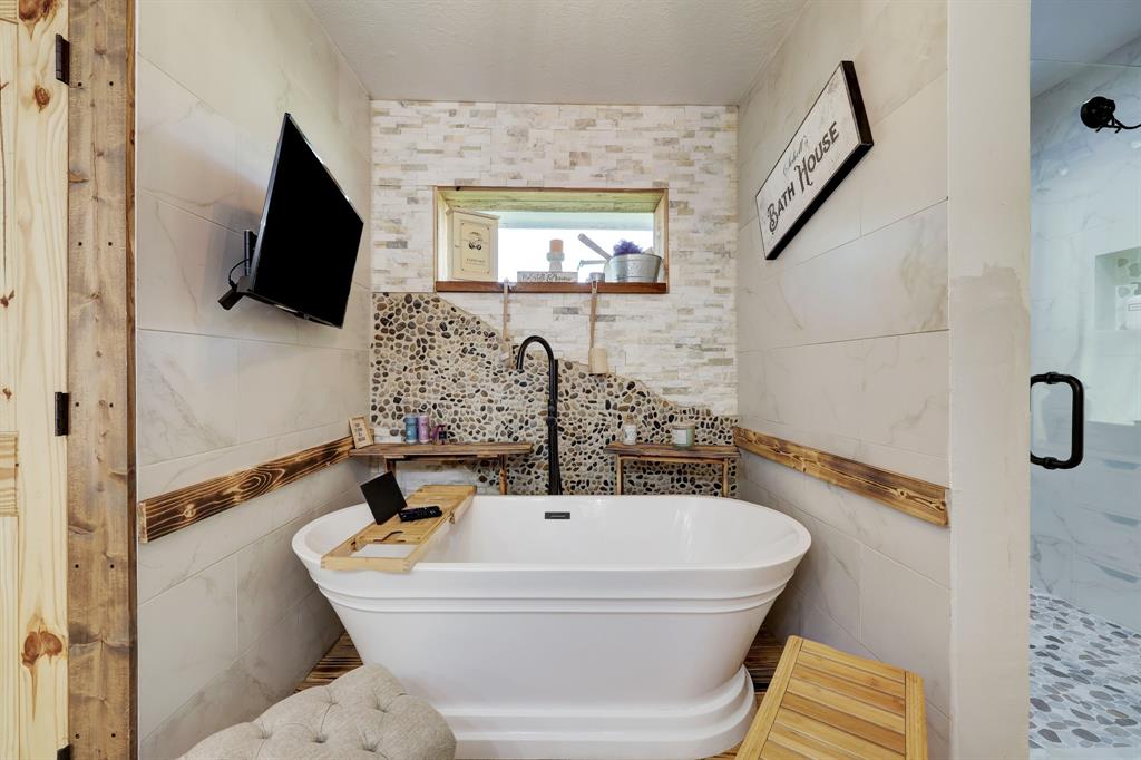 A closer view of this luxurious bath and glass shower. All the details this home has needs to be seen in person. Lovely designs of river rock and wood accents and built in shelving.