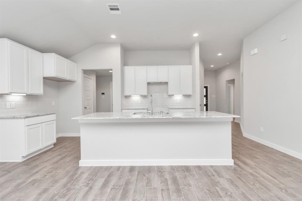 Culinary haven, featuring granite countertops, a tile backsplash, stainless steel appliances, 42” upper cabinets, and undercabinet lighting.