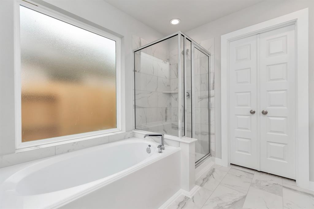 This additional view of the primary bath features a walk-in shower with the tile surround and separate garden tub perfect for soaking after a long day.