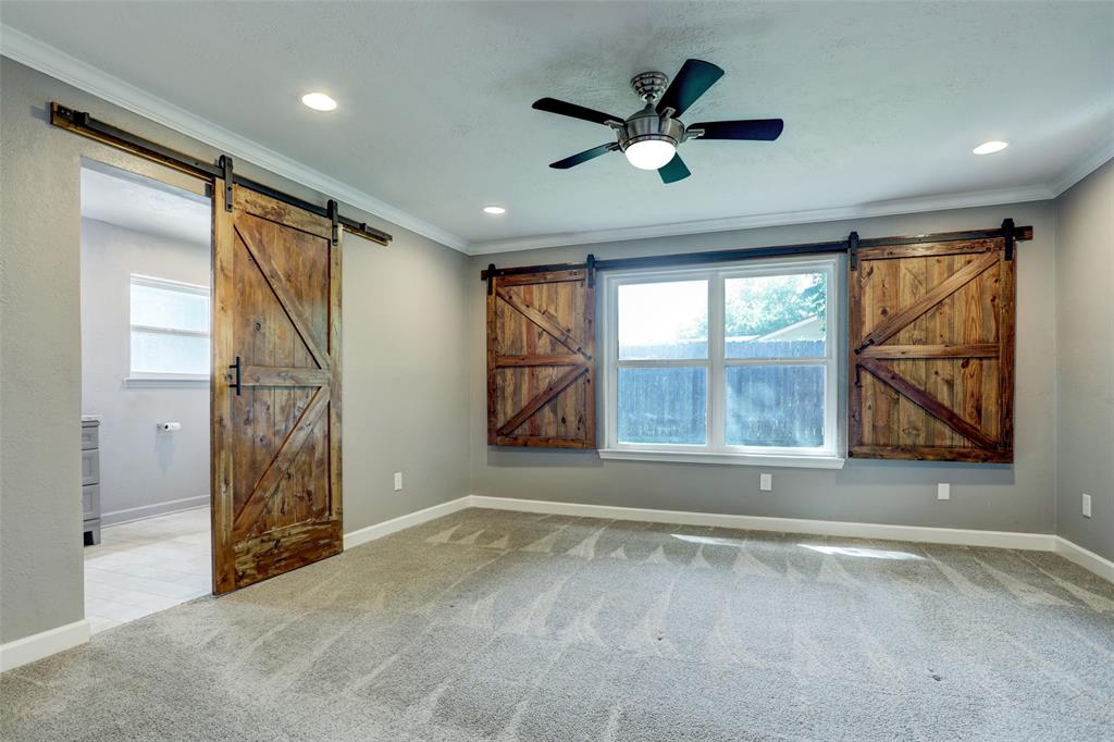 Vacant primary has energy efficient windows covered with barn door accented covering that easily slides over. NEW carpet too!