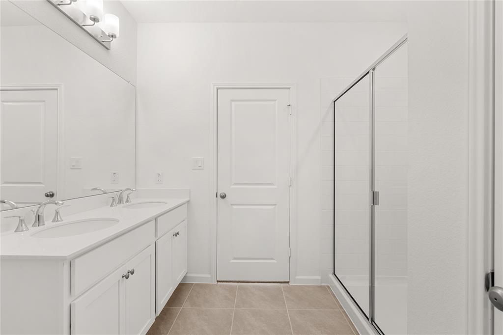 This additional view of your primary bathroom features tile flooring, fresh paint, walk-in shower, and a large walk-in closet.