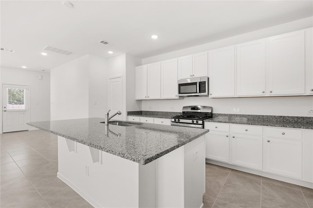 This light and bright kitchen features a large granite island, white cabinets, a large sink overlooking your family room, and recessed lighting.