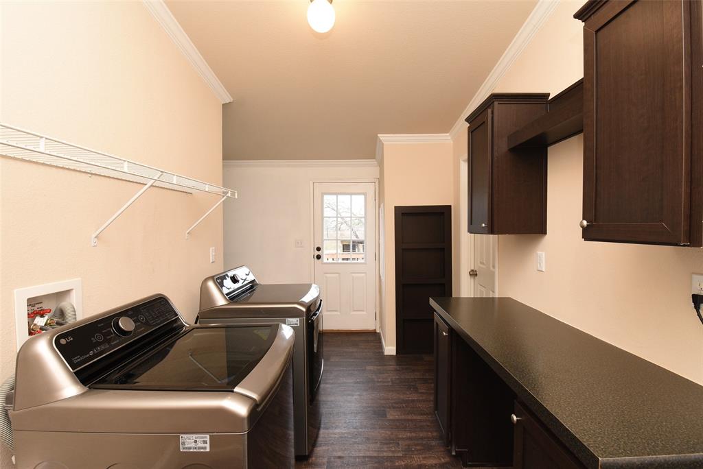 Laundry room area fits washer and dryer with room countertop area for folding and shelving/cabinets for storage.