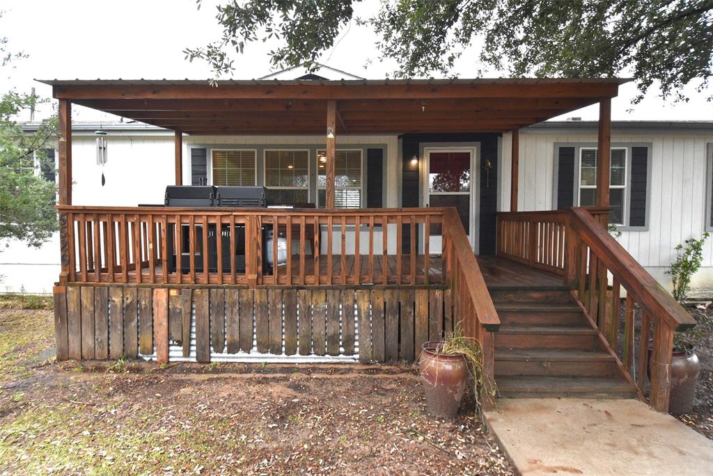 Nice stained covered wooden porch leading to the entrance of the house.