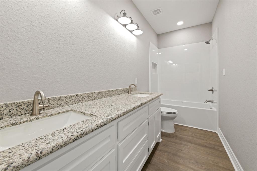 Spacious & Modern Secondary Bathroom features a sleek double sink vanity with ample storage & a tub/shower combo.