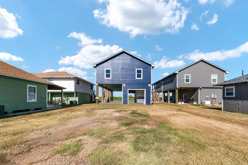 This beach house offers more than just stunning views; step into the versatile garage-turned-hangout space, complete with two garage doors for indoor-outdoor living. (View of property from the rear)