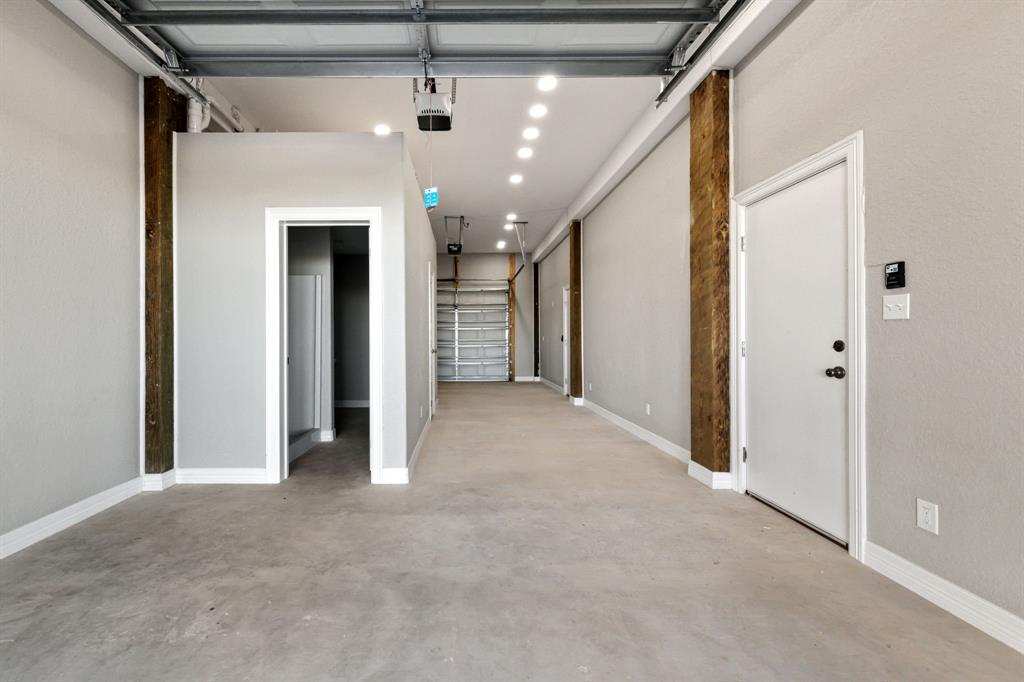 View from covered parking/driveway with rear garage door closed. Pictured: flex space, full bathroom & hallway leading to full kitchen.