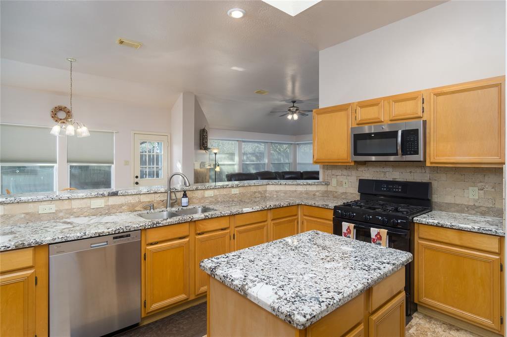 Spacious island kitchen with lots of granite countertops & lots of cabinet storage. SS dishwasher, microwave, plus gas range. View of backyard, breakfast room and family room from kitchen.