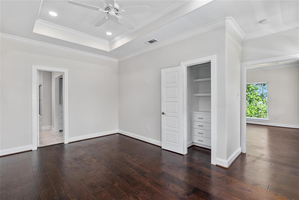 Primary bedroom with custom built-ins in one of the closets.  Notice the tray ceiling with recessed lighting