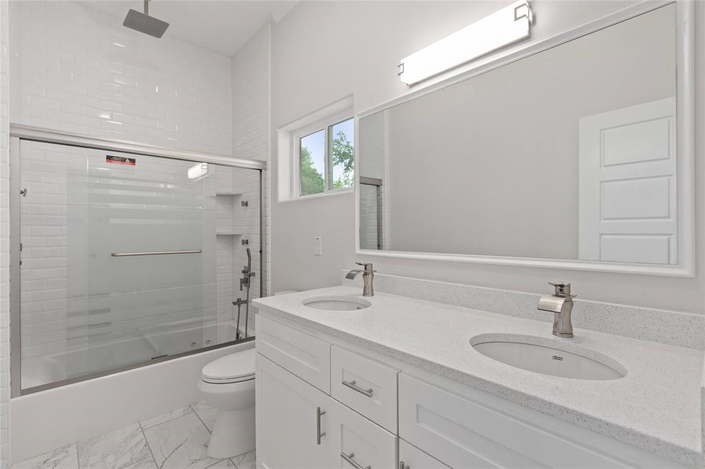 Secondary bathroom with dual sinks and whirlpool tub and multiple shower heads