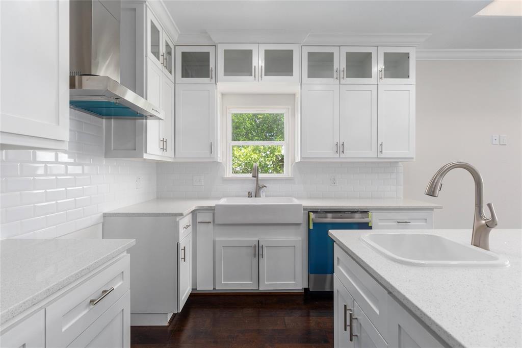 Quartz countertops with ample working space and custom cabinets with glass fronts at the top.