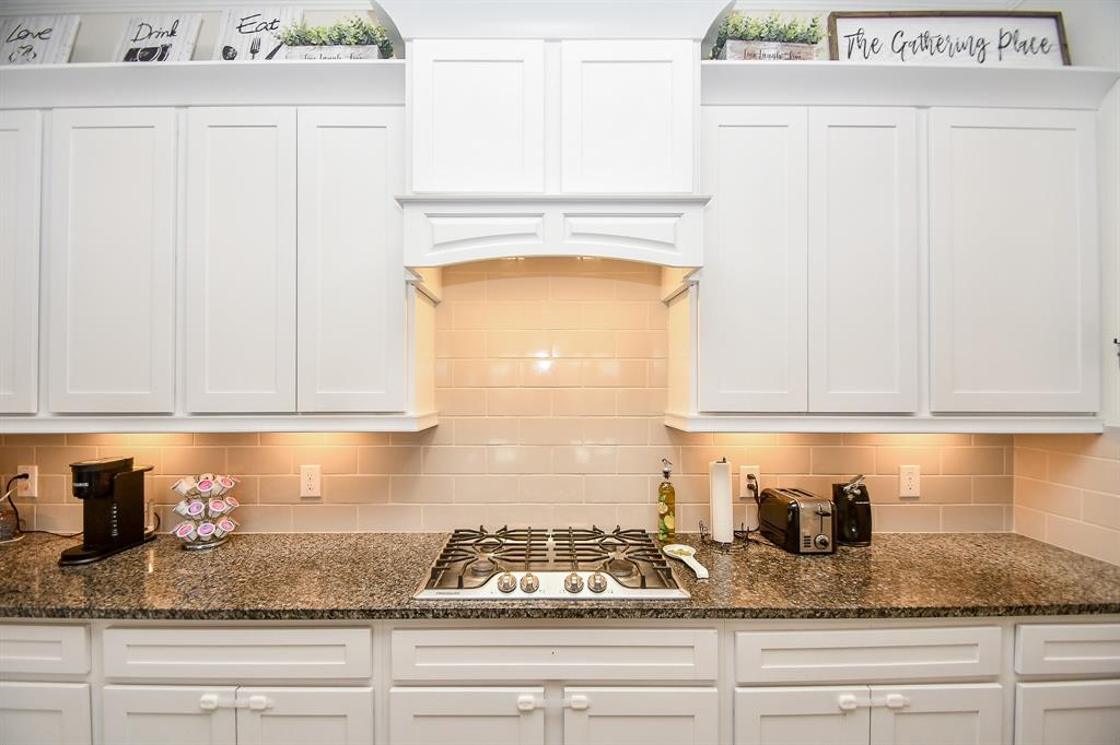 Beautiful granite countertops, tall cabinets, and a gas cooktop make this kitchen both functional and aesthetically pleasing, enhanced by its light and bright ambiance.